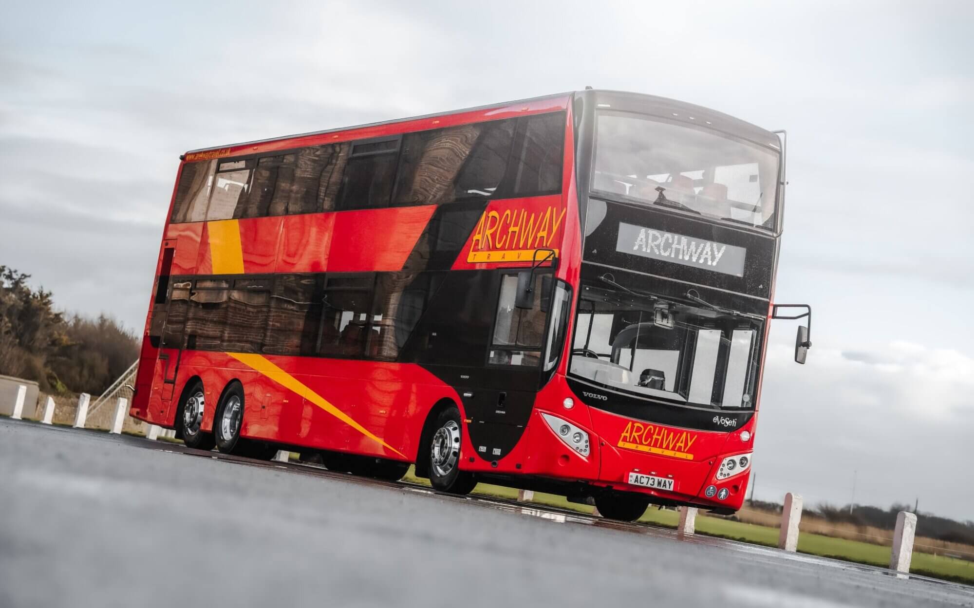 Red and yellow Archway Travel double decker bus shown on a road.